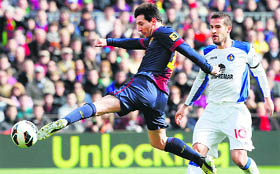 Barcelona's Lionel Messi shoots to score against Getafe's in Barcelona and Real Madrid's Cristiano Ronaldo.