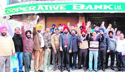 Members of the Amritsar Central Cooperative Bank Employees Union raise slogans during a strike inAmritsar on Monday.