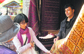 A customer has a close look at a carpet in the Surajkund crafts mela.