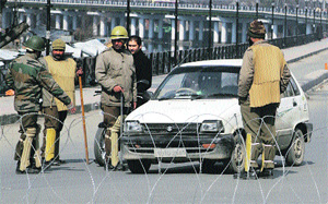 Securitymen stop a car during curfew at Dalgate in Srinagar on Tuesday. 