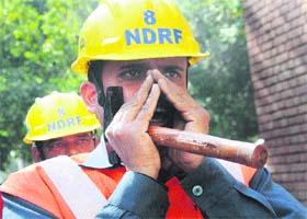 A member of the Disaster Management Authority team calls the victims to come out from the building during the disaster mock drill at the UT Secretariat in Chandigarh on Wednesday