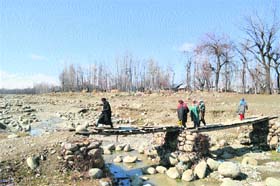 Unsafe crossing: People walk on a damaged footbridge at Chadoora village of Budgam district on Wednesday