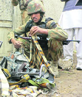A security official collects weapons near the police station in Bannu on Thursday.
