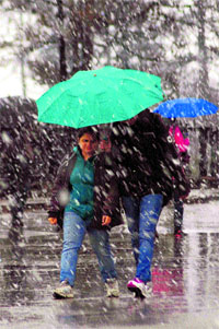 People walk during snowfall in Shimla on Friday.