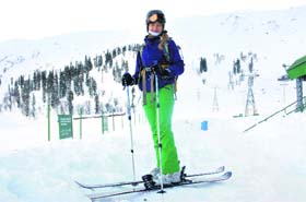 On her own trip: A skier walks over the snow at the ski resort in Gulmarg on Saturday