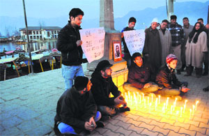 Students of University of Kashmir light candles to protest against the hanging of Afzal Guru on the banks of the Dal Lake in Srinagar on Sunday.