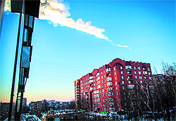 The trail of a falling object is seen above a residential apartment block in the Ural city of Chelyabinsk, on February 15