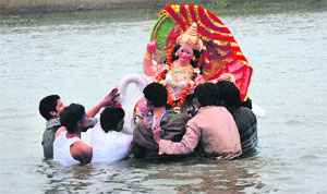 Devotees immerse a statue of Goddess Saraswati into a canal in Karnal. 