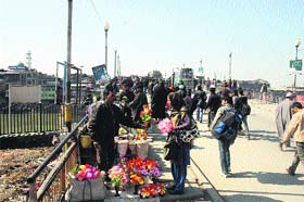Business as usual: A woman buys artificial flowers from a roadside vendor on the Amira Kadal bridge in Srinagar on Monday