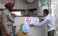 Health Department officials installing signs at a shop selling tobacco products in the city. A Tribune photograph