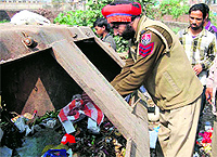 A policeman recovers a foetus dumped in a garbage bin at Dhogari village, located on the Pathankot road, near Jalandhar, on Wednesday