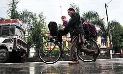 A man carries children on a bicycle after rain in Jammu on Thursday. Jammu city received 60 mm of rainfall in the last 48 hours with hailstorms