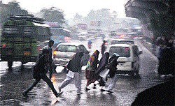 People run for cover during heavy rain at Dogra Chowk in Jammu on Thursday