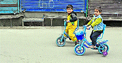 Children ride bicycles during the ongoing strike in Srinagar on Thursday