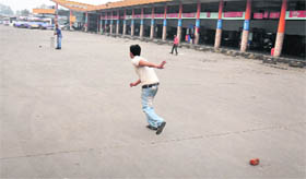 Youths play cricket at the deserted bus stand