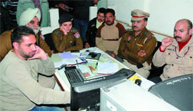 Senior police officials examine the CCTV footage of the PNB ATM from where an unidentified man stole Rs 7.80 lakh, in Bathinda on Friday.