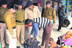 Police personnel frisk a passenger at Haridwar railway station on Friday in view of the twin bomb blasts in Hyderabad. Tribune photo: Rameshwar Gaur