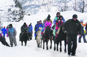 Tourists enjoy a horse ride after snowfall in the Solang valley on Friday.