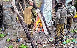 Security personnel try to keep themselves warm by burning wood in Srinagar on Friday