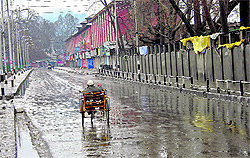 A physically challenged person rides a tricycle on a deserted road during curfew in Srinagar on Friday