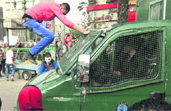 A protester jumps on a police vehicle as it passes by an anti-government protest in Cairo on Friday. President Mohamed Mursi on Thursday called parliamentary elections that will begin on April 27 and finish in late June.  Reuters 