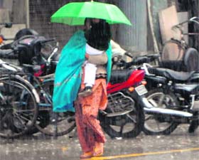 Rain pain: A woman brings back her child from the school in the rain in Amritsar on Saturday.