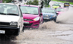 Vehicles wade through a flooded road during a heavy rain in the Jammu on Saturady