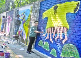 Artists make wall paintings during the Design The Change wall art event at Delhi University (North Campus) in New Delhi on Sunday