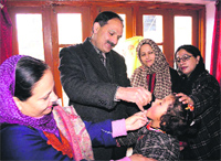 Kashmir Social Welfare Director Bashir A Bhar administers polio drops to a child in Srinagar. A Tribune photograph
