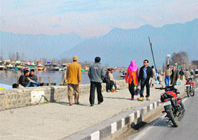 Tourists walk on a footpath near the Dal Lake in Srinagar on Monday.