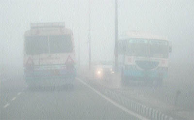 Vehicles make their way through the dense fog on the Chandigarh- Ambala highway at Zirakpur on Monday.