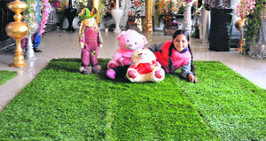 A girl poses for a photograph on a patch of artificial grass in a showroom.