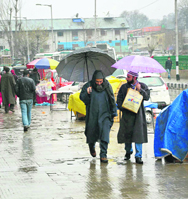 People walk with umbrellas during light showers in Srinagar on Tuesday. 