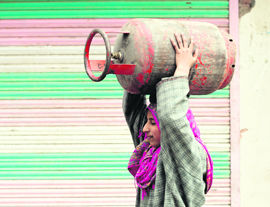 A girl walks with an LPG cylinder on her head in Budgam on Tuesday.