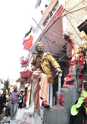 A policeman stands guard outside a demolished house