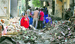 Residents sit on debris after a demolition drive in the Jawahar Nagar Camp area in Ludhiana on Thursday