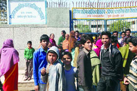 People gather outside the municipal government school in the Mangolpuri area where yesterday hundreds of protesters clashed with the Delhi police.
