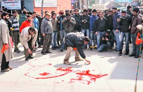 Supporters of the JKLF paint a road with red colour during a protest in Srinagar