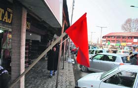 A man hoists a red flag oustside his shop in Srinagar