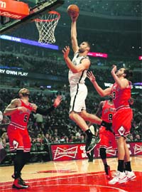 Brooklyn Nets' Brook Lopez (top) goes to the basket against Chicago Bulls' Joakim Noah (R) and Carlos Boozer (L) during the NBA game in Chicago, Illinois