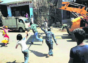 People attack a civic body employee after a man was injured when an electricity pole fell on him during an anti-encroachment drive in Allahabad on Monday. 
