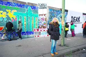 A woman stands in front of the so-called East Side Gallery, the Berlin Walls longest remaining section and now a outdoor gallery, to demonstrate against the dismantling of a segment to create new housing in Berlin on Monday