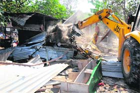 60 illegal sheds demolished: A machine pulls down sheds during a drive of the UT Estate Office in the Sector 37 rehri market in Chanidgarh on Tuesday