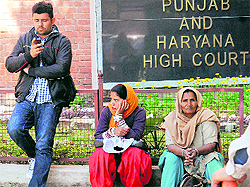 Litigants wait outside the Punjab and Haryana High Court in Chandigarh on Wednesday