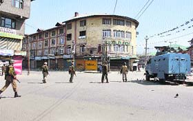 Paramilitary soldiers patrol a deserted street at Budshah Chowk in Srinagar on Wednesday