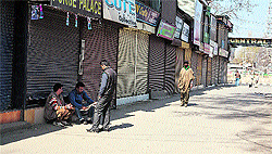 Shopkeepers read a newspaper in Srinagar on Wednesday