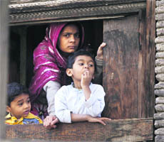 A woman along with two children looks at protesters who clashed with the police at Batmaloo in Srinagar on Thursday. 