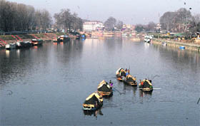 Boatmen collect sand along the banks of the Jhelum river in Srinagar on Thursday.