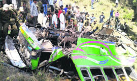 Locals and rescue workers near the mangled remains of the minibus in Rajouri district on Friday.
