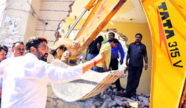 A man tries to stop MC officials from demolishing an illegal structure.